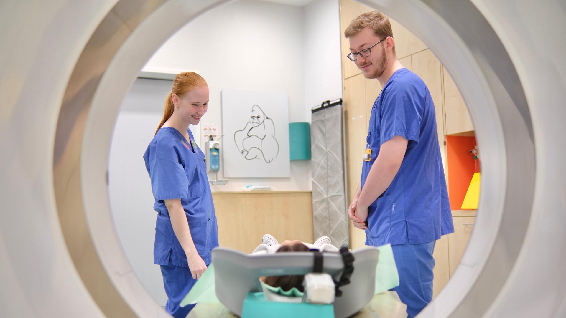 2 Kolleg*innen der Radiologie scannen einen Patienten